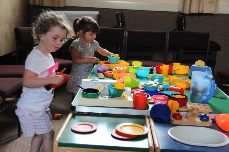 Young children playing with toy kitchen items.